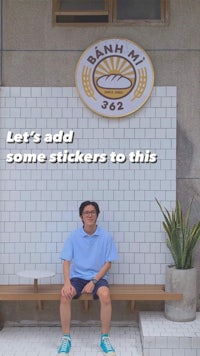 a man sitting on a bench next to a sign that says let's add some stickers to this