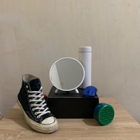 a pair of sneakers, a mirror and a bottle of water on a table