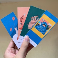 a person holding up a set of colorful bookmarks